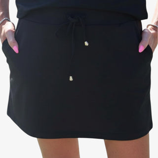 Women's black performance skort with side pockets, adjustable drawstring waist and gold-tone tips, shown in a front detail view.