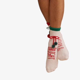 Beige socks with red text and green accents worn by a person on a white background