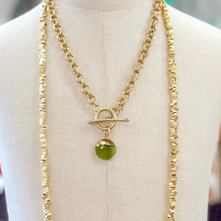 Green gemstone gold filled pendant necklace with toggle clasp layered with chain necklaces on mannequin
