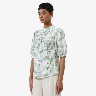 White blouse with green floral print, smocked neckline and puff sleeves styled with cream high waisted trousers