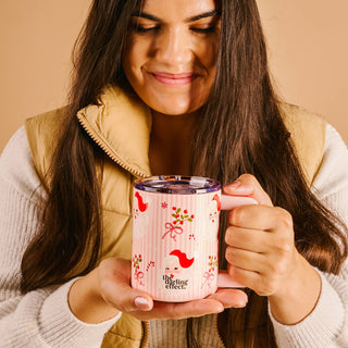 Woman holding a mug with a decorative design against a beige background
