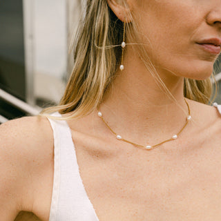 Gold threader earrings with freshwater pearls dangling from a delicate chain