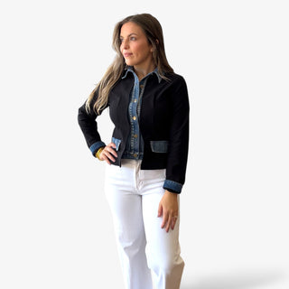 Woman wearing a black jacket with denim accents with white jeans on a white background