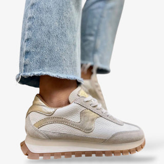 white leather sneaker with gold metallic detail and gum sole paired with cuffed wide leg jeans side view