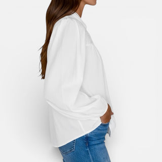 Person wearing a white oversized sweater and blue jeans on a plain background