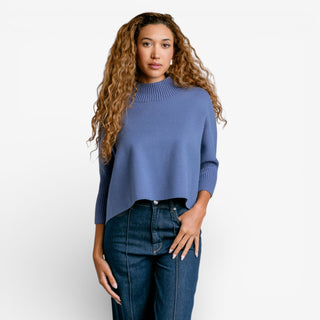 Woman wearing a blue sweater and jeans on a white background