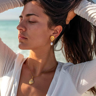 Gold amulet pendant necklace with crystal accents on model outdoors close-up lifestyle view