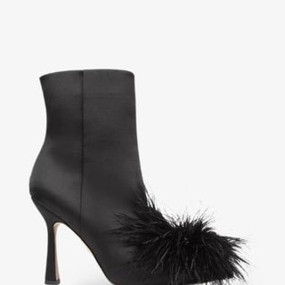 Black satin ankle boot with pointed toe, mid heel, and statement feather detail across the front for a bold, chic evening look.