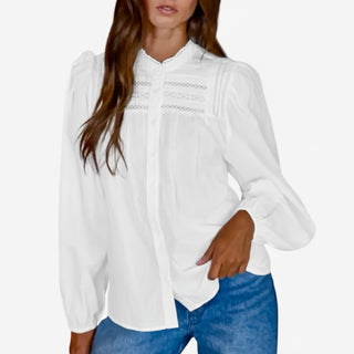 Woman wearing a white blouse with lace details and blue jeans on a white background