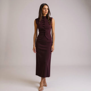 Woman wearing a top and high waist skirt  against a plain background