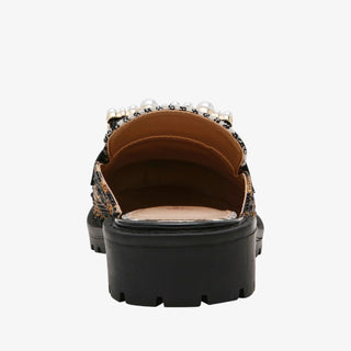 Back view of a black platform shoe with decorative elements on a white background