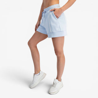 Blue scuba knit A-line shorts with contrast piping and relaxed fit shown with side view.