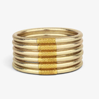 A stack of six BudhaGirl All Weather Bangles in  Etoile muted goldwith textured geometric patterns on the center bands, set against a clean white background.