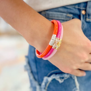 BudhaGirl Valentina Three Kings Bangles set with pink, hot pink and coral all weather bangles featuring crystal-accented gold and rose gold details on models arm.