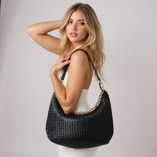 Woman holding the black Pretty Simple Sienna Slouchy Woven Shoulder Bag with gold chain detail.