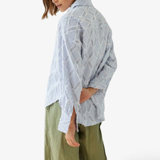 Blue oversized button down shirt with blue stripe texture and fringe detail side profile back view