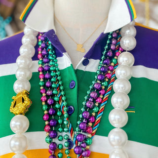 Mannequin wearing a colorful shirt with beads draped over it and gold Louisiana necklace 
