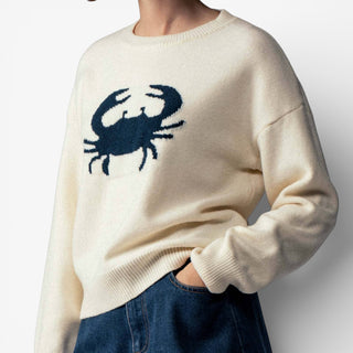 Beige sweater with a blue crab design on a plain background