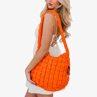 Woman holding an orange quilted handbag on a white background