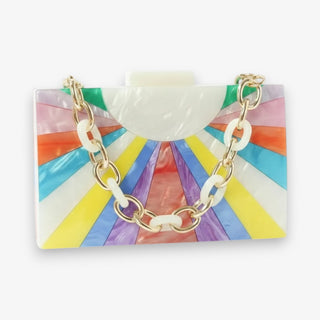 Celeste acrylic clutch bag with colorful rainbow sunburst design, pearlized finish, gold chain strap, and statement box silhouette front view for vacation outfits.