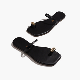 Black sandals with gold accents on a white background