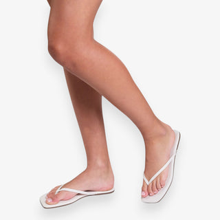 White flip-flops worn by a person on a white background