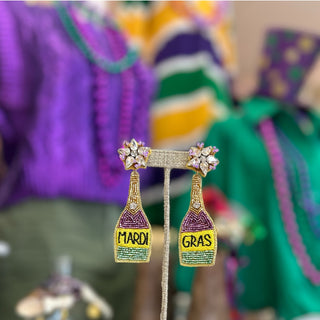 Mardi Gras-themed earrings on a stand with colorful blurred background