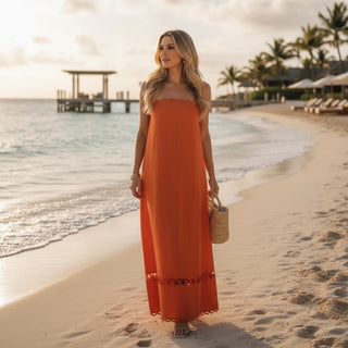 Orange scallop trim strapless maxi dress on tropical beach with flowy silhouette and resort vacation styling