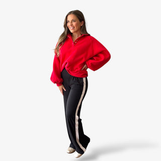 Red Felicity sweatshirt with snap detail and balloon sleeves worn with black side stripe track pants.