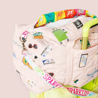 Queen of sparkle ivory travel duffle bag with sequins and travel icons close up view with adjustable shoulder strap for weekend travel