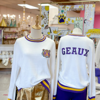 Two mannequins wearing white sweater with a tiger logo and 'GEAUX' text in a sequins in a store setting.