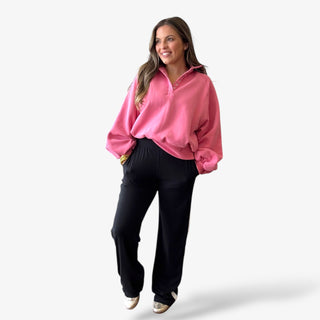 Lady wearing black track pants and pink sweatshirt with balloon sleeves and snap button details on a white background