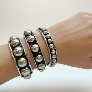 Statement black and silver stretch bracelet in three sizes worn by a model on a white background 