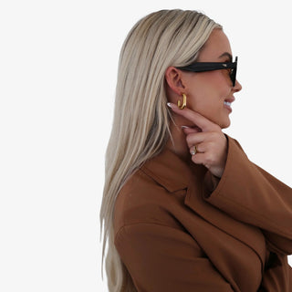 Small oval hoop earrings in 18K gold plated stainless steel with polished gold finish on neutral background