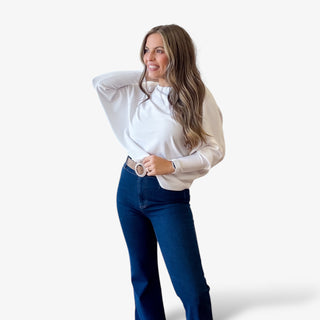 Woman wearing the kerisma Ryu white sweater and blue pants on a white background