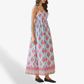 Side view of blue floral maxi dress with pink botanical print, square neckline, adjustable spaghetti straps, flowy tiered skirt, and decorative border hem.
