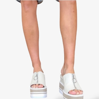 White platform slide sandals with chunky striped sole, front zipper detail, and open toe design for a bold, modern, and elevated casual look.