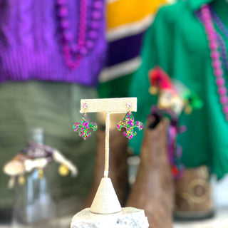 Colorful earrings on a stand with a blurred background of boots and colorful clothing.
