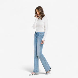 Woman wearing high rise light wash bootcut jeans with white long sleeve top and silver heels