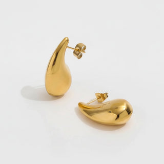 Gold teardrop earrings on a light gray background