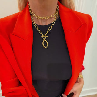 Person wearing a red blazer and black top with gold chain necklace.