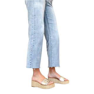 Lady wearing light blue jeans and Sam Edelman Pauleena gold platform sandals on a white background