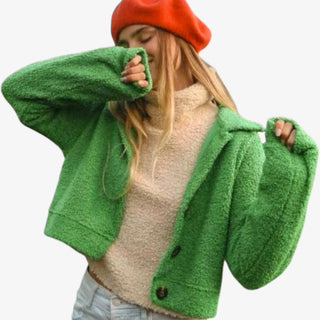 Person wearing a green cardigan over a beige sweater with a red beanie on a white background