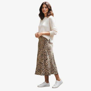 Woman wearing a white sweater and leopard print skirt on a white background