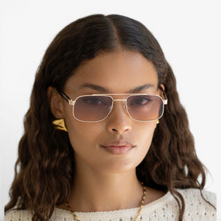 Model wearing FREYRS Vesper aviator sunglasses with gold frame and sunset gradient lenses lifestyle view