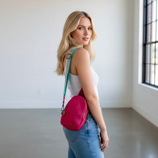 Fuchsia crossbody sling bag with adjustable patterned strap worn on model back view