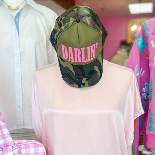 Green camouflage cap with 'DARLIN'' text on a mannequin in a store setting