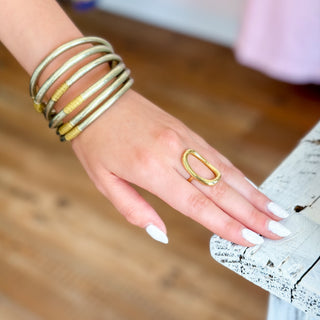 Gold oval statement ring on hand with polished open design styled on white distressed table close-up view