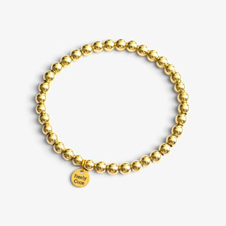 Gold filled beaded bracelets in polished gold with mixed bead sizes, shown stacked together on a white marble background