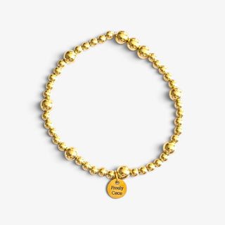 Gold filled beaded bracelets in polished gold with mixed bead sizes, shown stacked together on a white marble background